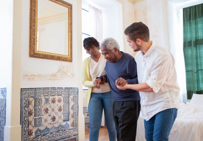 Two carers helping an elderly man